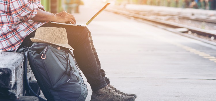 Person med ryggsäck som sitter på tågstation