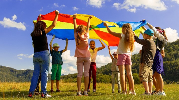 Barn står i ring och håller upp ett fallskärmstyg