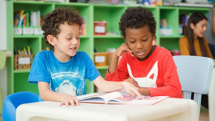 Två barn läser i samma bok
