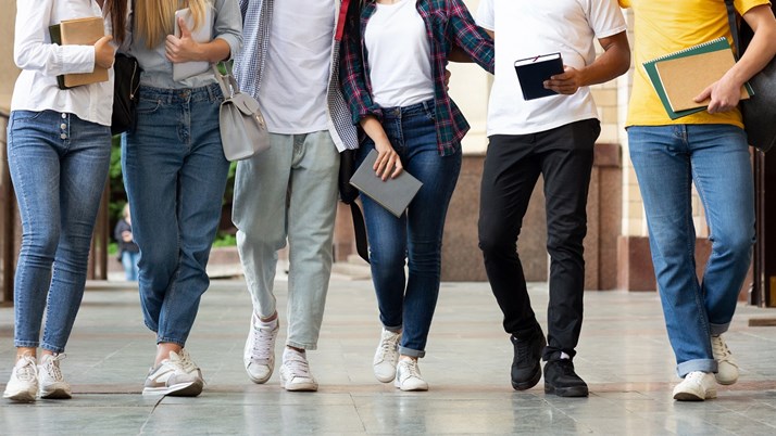 Sex ungdomar går mot kameran i en skolkorridor