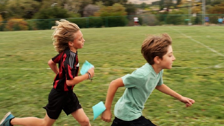Två barn springer över en fotbollsplan